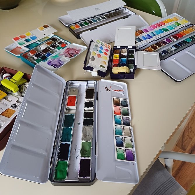 Five watercolour palettes, containing half and full pans of paint.