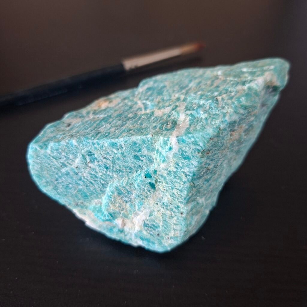 A turquoise mineral with white stripes in a criss-cross pattern.