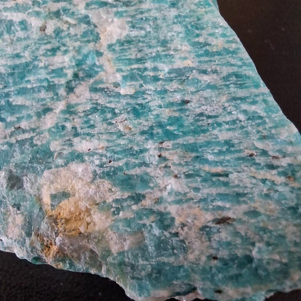 A close-up of a turquoise mineral showing white stripes in a criss-cross pattern.