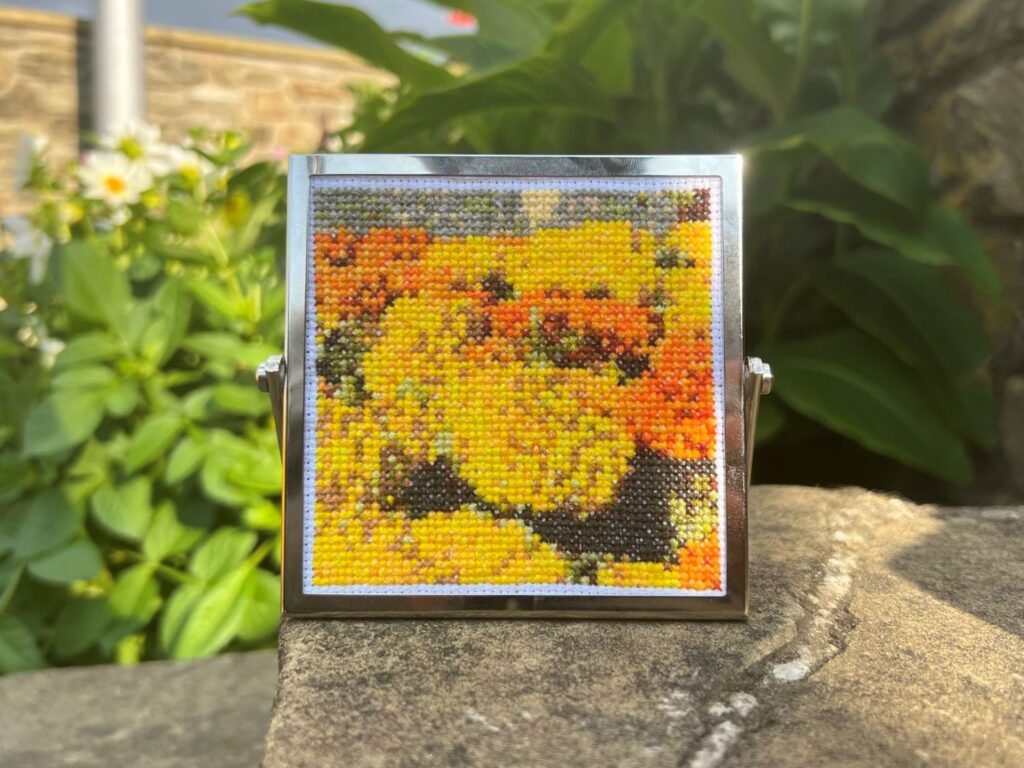 'Flower Bed' by Paulina Kurzydlowska - a cross stitch of yellow and orange flowers.