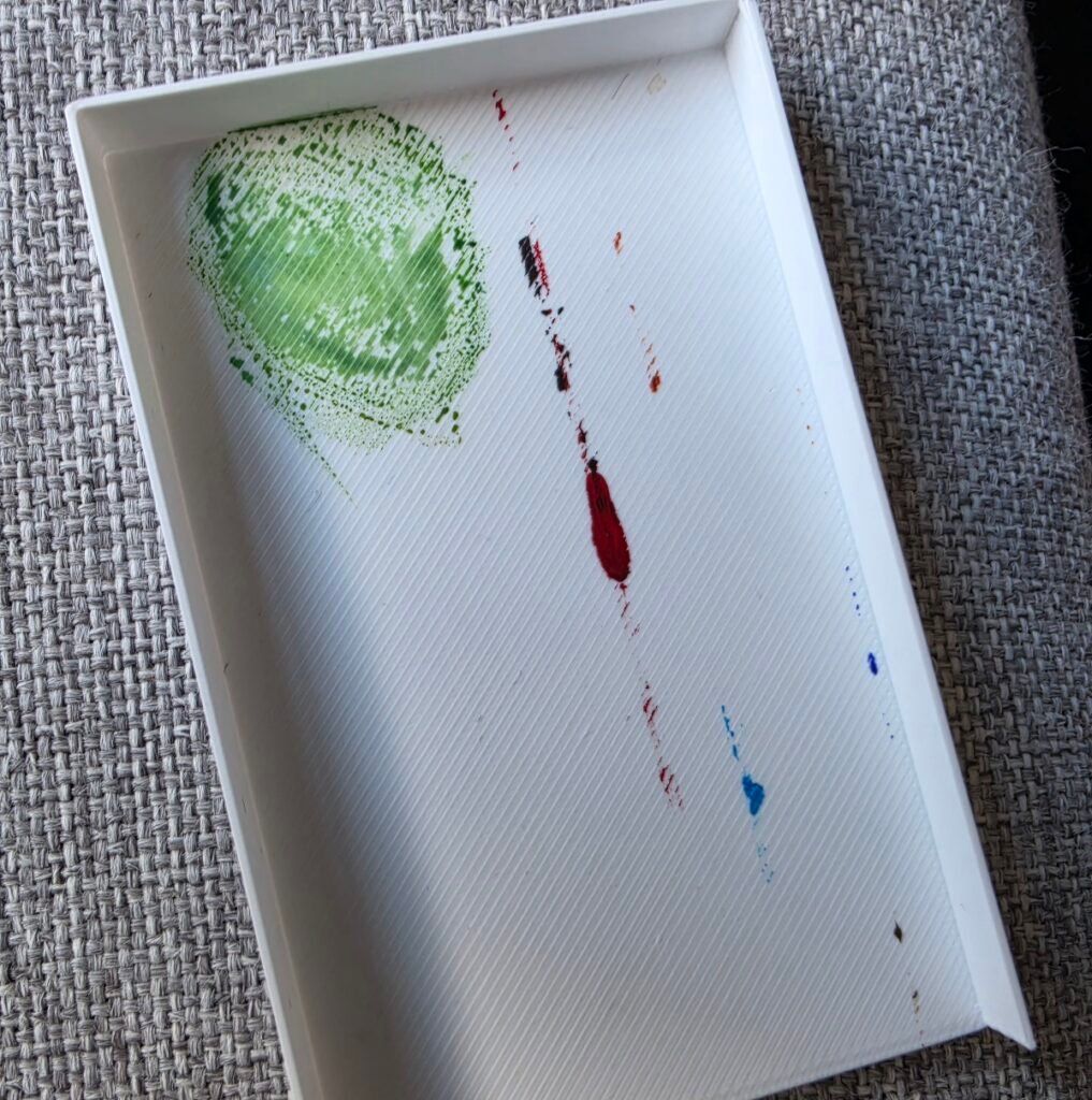 The inside of the lid of the palette, showing the small amount of mixing that I did here and the paint marks from the over-filled wells.