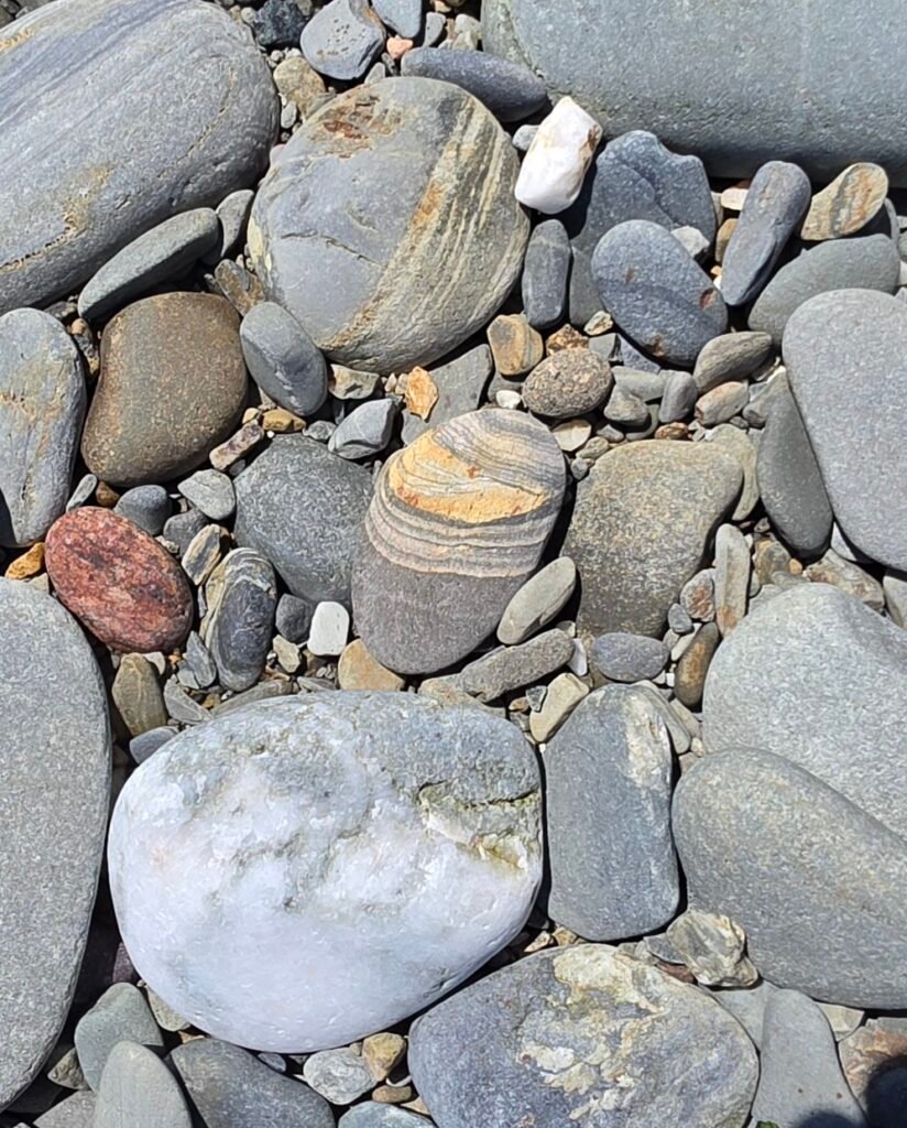 Orange and grey pebbles on a beach.