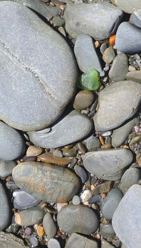 Green seaglass on a pebbly beach.