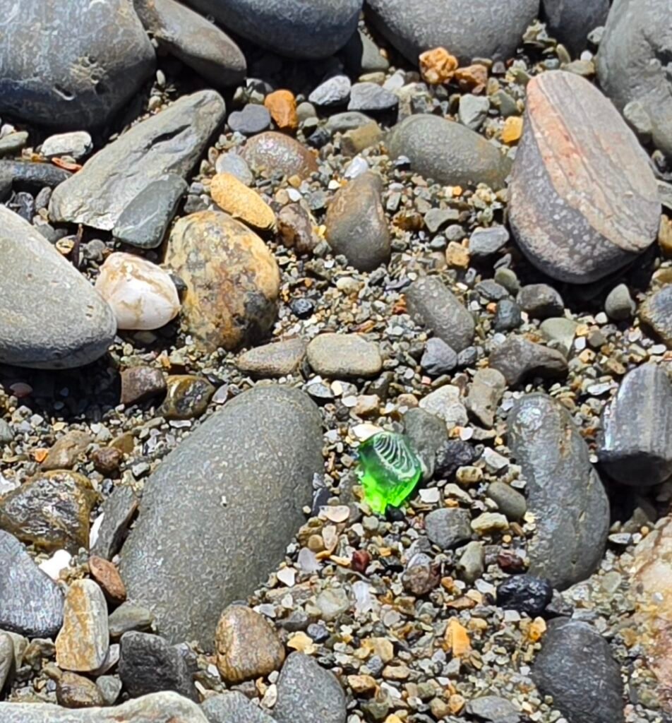 Green seaglass on a pebbly beach.