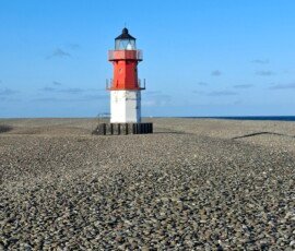 Winkie lighthouse, Point of Ayre A red and white small lighthouse on a pebble beach.